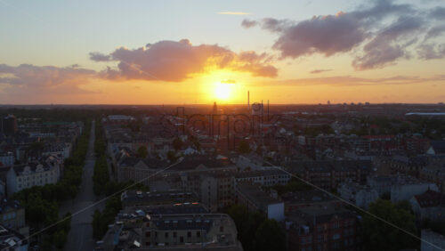 Copenhagen, Denmark – August 3, 2025: Aerial drone view of tree lined streets, historic architecture, and the sun casting a warm glow across the skyline of the city - Starpik Stock