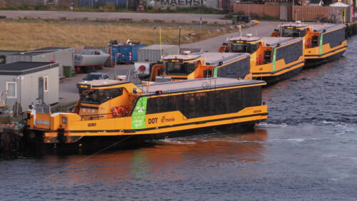 Copenhagen, Denmark – August 3, 2025: Aerial drone view of yellow harbor buses lined up and sailing in Copenhagen’s canals - Starpik Stock