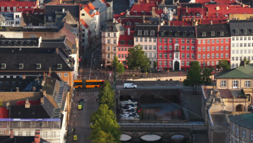 Copenhagen, Denmark – August 3, 2025: Aerial view of the Nybrogade Street lined with colorful historic houses, trees, and docked boats on a canal - Starpik Stock