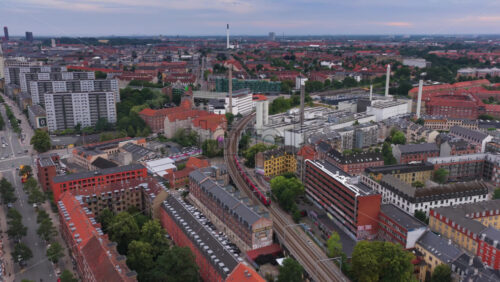Copenhagen, Denmark – August 4, 2025: Aerial drone shot of a red S-train traveling across the elevated railway near Norrebro Station - Starpik Stock