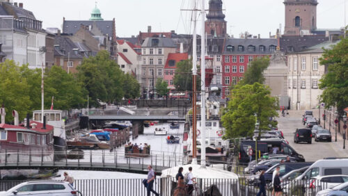 Copenhagen, Denmark – August 4, 2025: Aerial drone view in Christianshavn, Copenhagen, with boats, cyclists, and pedestrians along the bridges - Starpik Stock