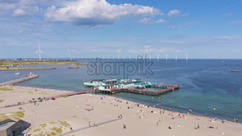 Copenhagen, Denmark – August 4, 2025: Aerial drone view of Amager Strandpark beaches and promenade with Middelgrunden wind turbines lined across the horizon - Starpik Stock