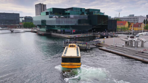 Copenhagen, Denmark – August 4, 2025: Aerial drone view of BLOX cultural and architectural hub with a yellow Copenhagen harbor bus departing from the quay - Starpik Stock