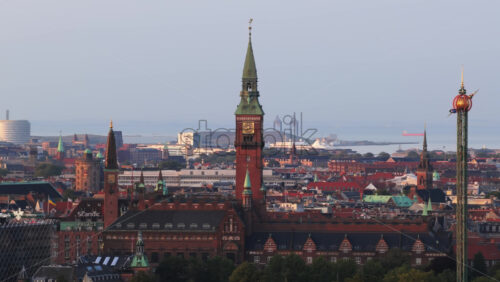 Copenhagen, Denmark – August 4, 2025: Aerial drone view of Copenhagen’s historic red-brick City Hall tower with Tivoli Gardens’ rides and the harbor in the background - Starpik Stock