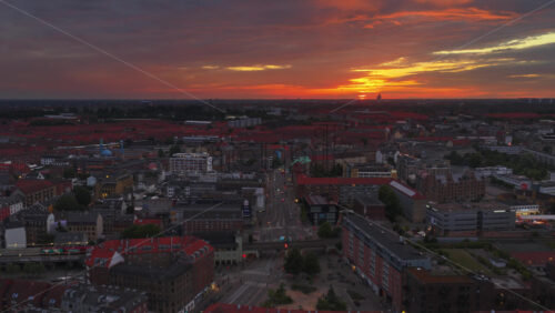 Copenhagen, Denmark – August 4, 2025: Aerial drone view of Norrebro Station with red S-train passing by, captured during sunset with orange skies - Starpik Stock