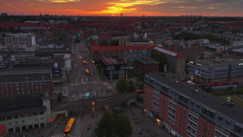 Copenhagen, Denmark – August 4, 2025: Aerial drone view of Norrebro Station with red S-train passing by, captured during sunset with orange skies - Starpik Stock