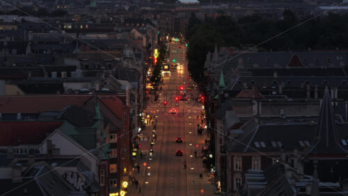 Copenhagen, Denmark – August 4, 2025: Aerial drone view of Norrebrogade at night with cars, cyclists, and neon shop signs lighting up the bustling street - Starpik Stock
