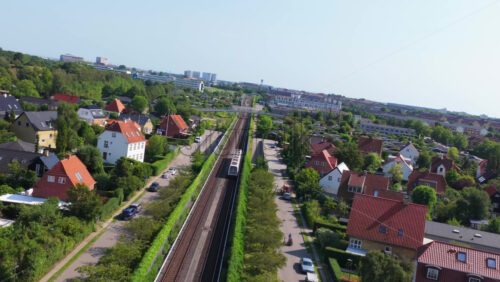 Copenhagen, Denmark – August 4, 2025: Aerial drone view of Oresund Metro Station from above, with a train arriving and cyclists on the overpass - Starpik Stock
