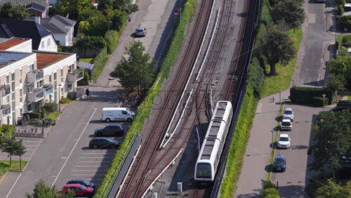 Copenhagen, Denmark – August 4, 2025: Aerial drone view of Oresund Metro Station from above, with a train arriving and cyclists on the overpass - Starpik Stock