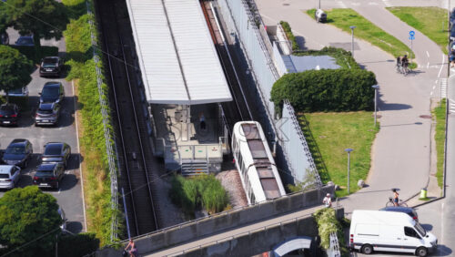 Copenhagen, Denmark – August 4, 2025: Aerial drone view of Oresund Metro Station from above, with a train arriving and cyclists on the overpass - Starpik Stock