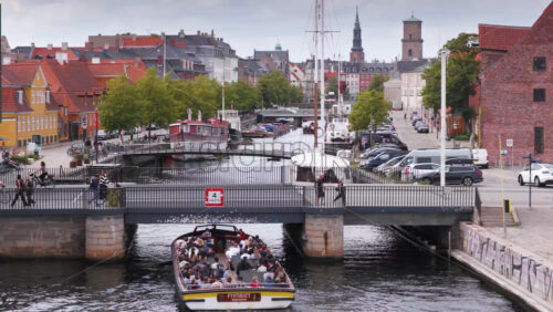 Copenhagen, Denmark – August 4, 2025: Aerial drone view of a tourist boat passing under the bridge next to BLOX, with historic Copenhagen houses and canals in the background - Starpik Stock