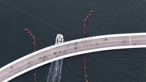 Copenhagen, Denmark – August 4, 2025: Aerial drone view of cyclists and pedestrians filling the curved bridge, shot directly from above against the deep blue water - Starpik Stock