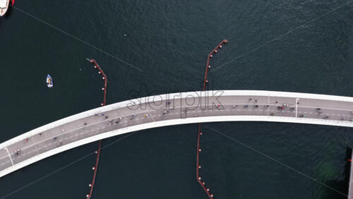 Copenhagen, Denmark – August 4, 2025: Aerial drone view of cyclists and pedestrians filling the curved bridge, shot directly from above against the deep blue water - Starpik Stock