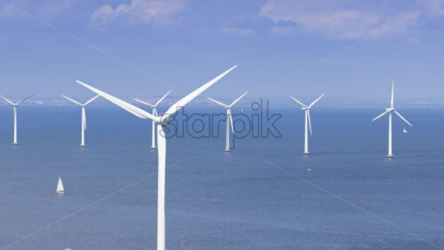 Copenhagen, Denmark – August 4, 2025: Aerial drone view of offshore wind turbines spinning in the sea at the Oresund Wind Farm - Starpik Stock