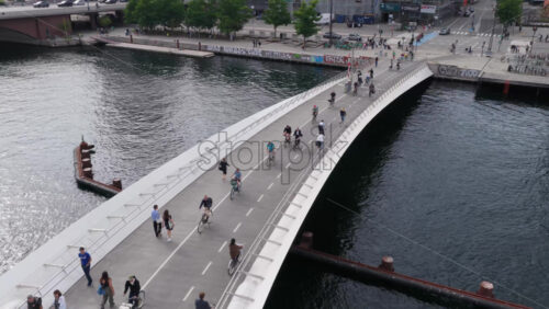 Copenhagen, Denmark – August 4, 2025: Aerial drone view of the curved pedestrian and cycling bridge spanning Copenhagen’s harbor, with Langebro bridge behind - Starpik Stock