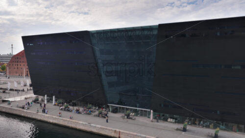 Copenhagen, Denmark – August 4, 2025: Aerial drone view of the modern glass extension of the Royal Danish Library, overlooking Copenhagen’s waterfront - Starpik Stock
