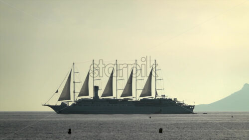Distant view of a large multi-mast sailing ship gliding across the Mediterranean Sea at sunset with mountains on the background - Starpik Stock