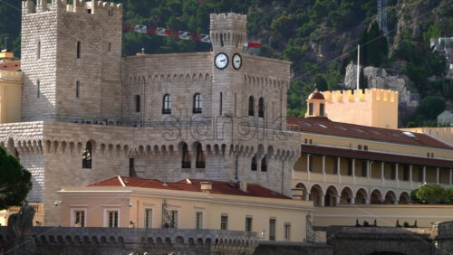 Distant view of the Prince’s Palace of Monaco and medieval ramparts perched above Monaco, with visitors walking around - Starpik Stock