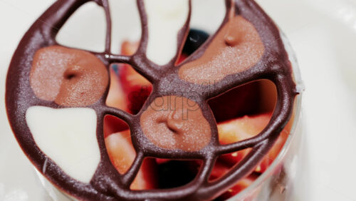 Elegant dessert in a glass topped with fresh strawberries, blueberries, and a chocolate lattice decoration - Starpik Stock