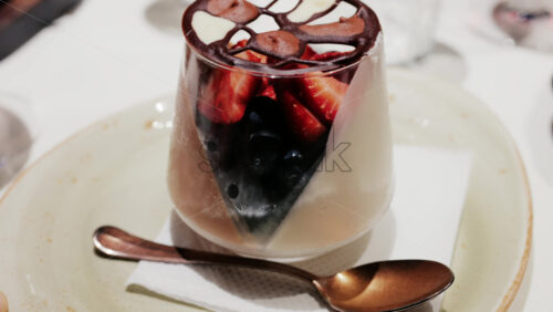 Elegant dessert in a glass topped with fresh strawberries, blueberries, and a chocolate lattice decoration - Starpik Stock