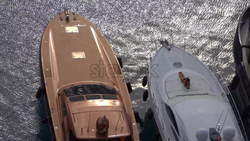 Fontvieille, Monaco – July 4, 2025: Close-up of luxury yachts docked in the marina, with a woman sunbathing on the deck - Starpik Stock