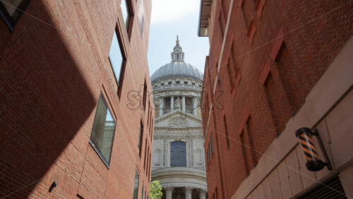 Framed view of St. Paul’s Cathedral dome between two modern brick buildings in London, England - Starpik Stock