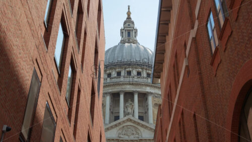 Framed view of St. Paul’s Cathedral dome between two modern brick buildings in London, England - Starpik Stock