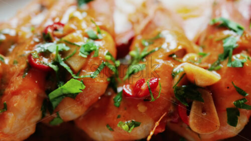 Garlic prawns in a rich sauce topped with herbs on a white plate - Starpik Stock