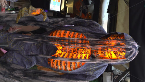 Glowing orange ribcage Halloween decoration wrapped in tattered fabric and cobwebs. Vertical - Starpik Stock