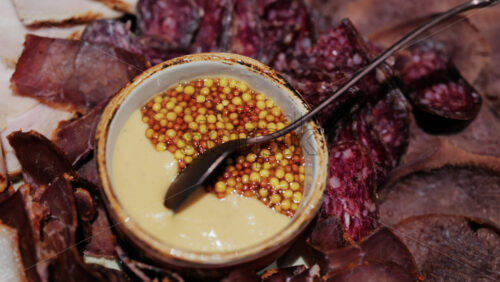 Gourmet charcuterie board with assorted cured meats, smoked slices, and a mustard seed sauce served in a bowl - Starpik Stock