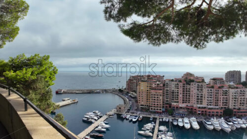 High-angle view of Port de Fontvieille in Monaco, showcasing colorful buildings, luxury yachts, and the surrounding mountainous landscape - Starpik Stock