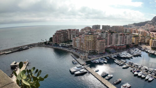 High-angle view of Port de Fontvieille in Monaco, showcasing colorful buildings, luxury yachts, and the surrounding mountainous landscape - Starpik Stock