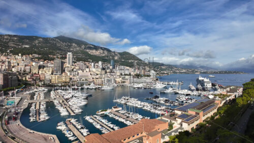 High-angle view of Port de Fontvieille in Monaco, showcasing colorful buildings, luxury yachts, and the surrounding mountainous landscape - Starpik Stock