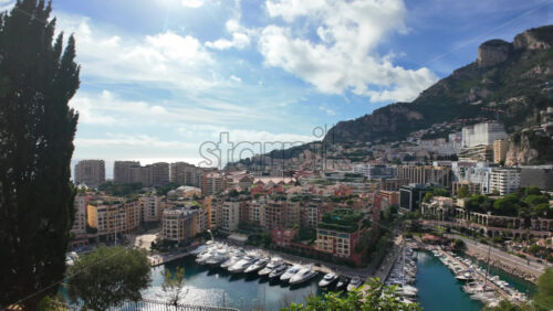 High-angle view of Port de Fontvieille in Monaco, showcasing colorful buildings, luxury yachts, and the surrounding mountainous landscape - Starpik Stock