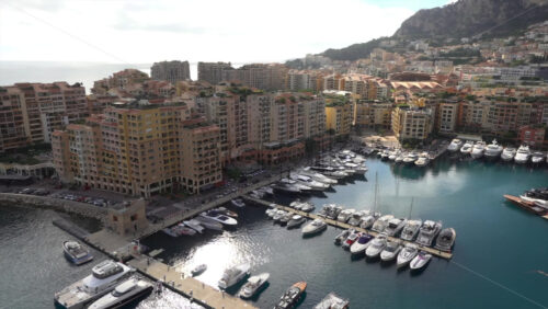High-angle view of Port de Fontvieille in Monaco, showcasing colorful buildings, luxury yachts, and the surrounding mountainous landscape - Starpik Stock