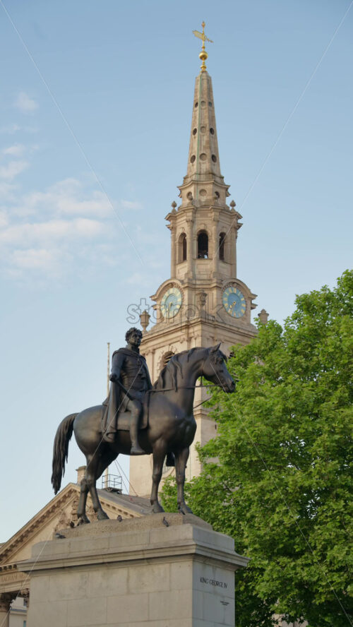 Iconic equestrian statue of King George IV with a church clock tower in the background during a bright day. Vertical, London - Starpik Stock