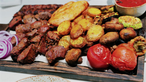 Juicy grilled meat served with golden roasted potatoes, tomatoes, mushrooms, and sauce - Starpik Stock