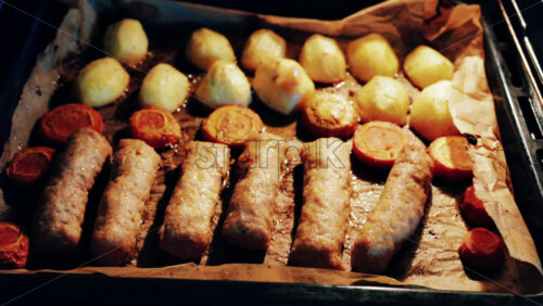 Juicy meat rolls grilling in the oven alongside carrots and potatoes, sizzling in high heat - Starpik Stock