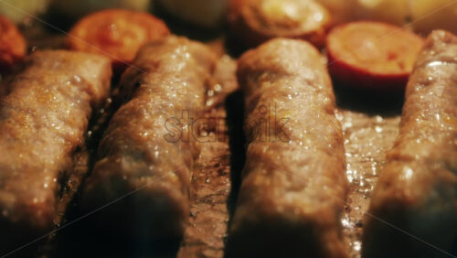 Juicy meat rolls grilling in the oven alongside carrots and potatoes, sizzling in high heat - Starpik Stock