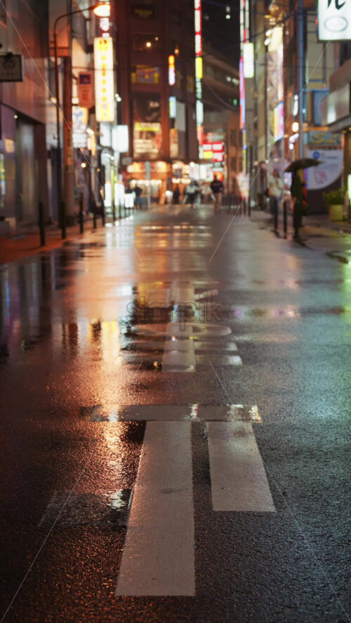 Kyoto, Japan – April 11, 2025: Blurred view of people walking on the streets of Tokyo, Japan on a rainy evening. Vertical - Starpik Stock