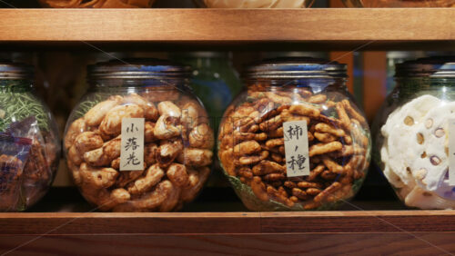 Kyoto, Japan – April 11, 2025: Close up of seed jars for sale at the Asakusa, Kannon Dori Market. Translation: “Small falling flowers, persimmon seeds” - Starpik Stock