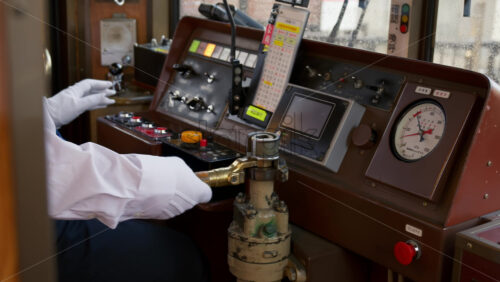 Kyoto, Japan – April 11, 2025: Conductor operating the tram towards Arashiyama, Japan. Translation: “Tail light, one-man entrance/exit” - Starpik Stock