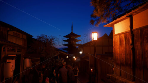 Kyoto, Japan – April 11, 2025: Distant view of the Yasaka Shrine from the Ninenzaka street with people walking in the evening - Starpik Stock
