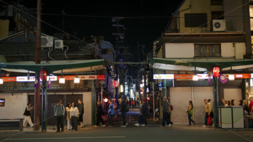 Kyoto, Japan – April 11, 2025: People walking on the streets of the Gion area in the evening. Translation: “Taste is good” - Starpik Stock