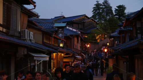 Kyoto, Japan – April 11, 2025: People walking through Ninenzaka stone-paved pedestrian road, lined with traditional buildings and shops in the evening. Translation: “Dead end ahead” - Starpik Stock
