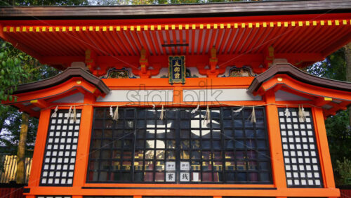 Kyoto, Japan – April 11, 2025: Stone torii gate at the Yasaka shrine surrounded by cherry blossom trees at sunset. Translation: “Shrine of the Beautiful Lady” - Starpik Stock