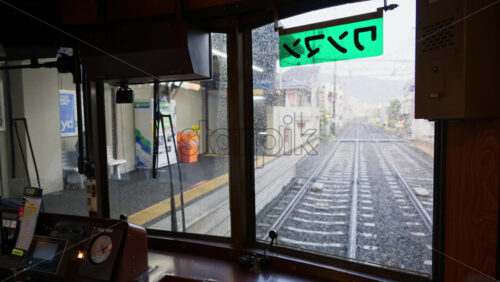 Kyoto, Japan – April 11, 2025: Tram towards Arashiyama arriving at the Shijo-Omiya Station with people waiting on a rainy day. Translation: “one-man” - Starpik Stock
