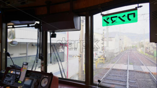 Kyoto, Japan – April 11, 2025: Tram towards Arashiyama leaving from the Shijo-Omiya Station with people waiting on a rainy day. Translation: “one-man” - Starpik Stock
