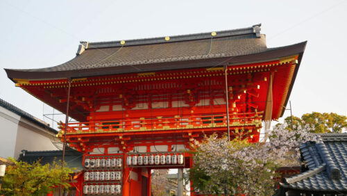 Kyoto, Japan – April 11, 2025: View of the Yasaka shrine surrounded by cherry blossom trees in daylight. Translation: “Names of local businesses and donors” - Starpik Stock