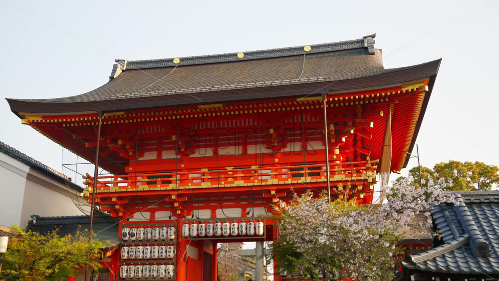 Kyoto, Japan – April 11, 2025: View of the Yasaka shrine surrounded by cherry blossom trees in daylight. Translation: “Names of local businesses and donors” - Starpik Stock